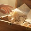 рука подростка тянется к открытому сундучку с его детскими вещами, которые сохранили родители